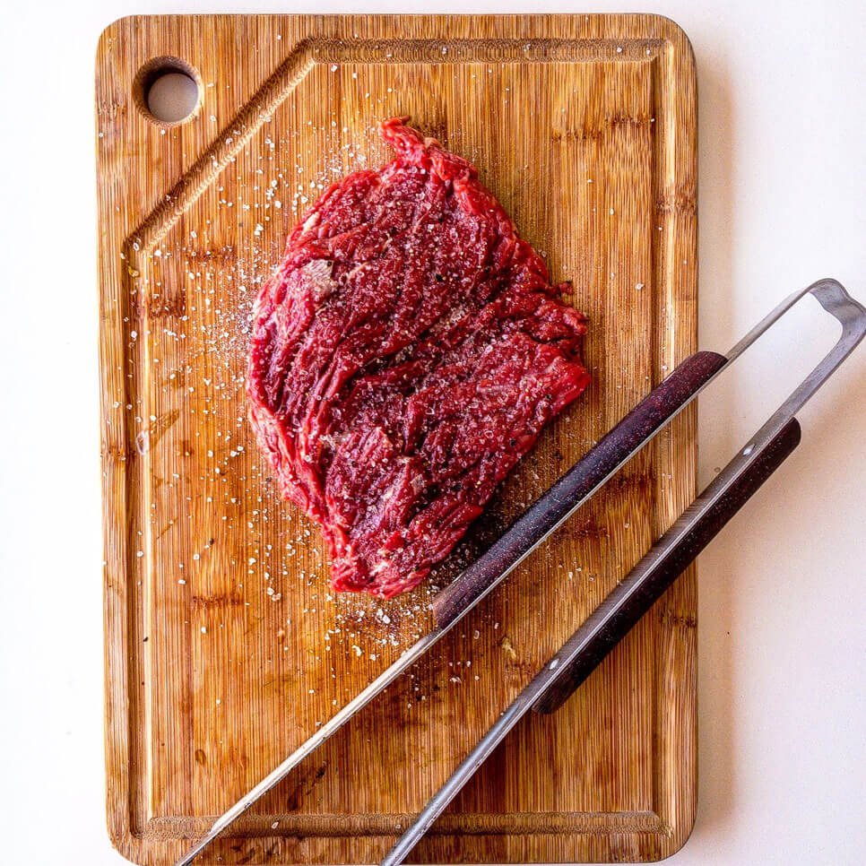 A piece of meat on top of a cutting board.