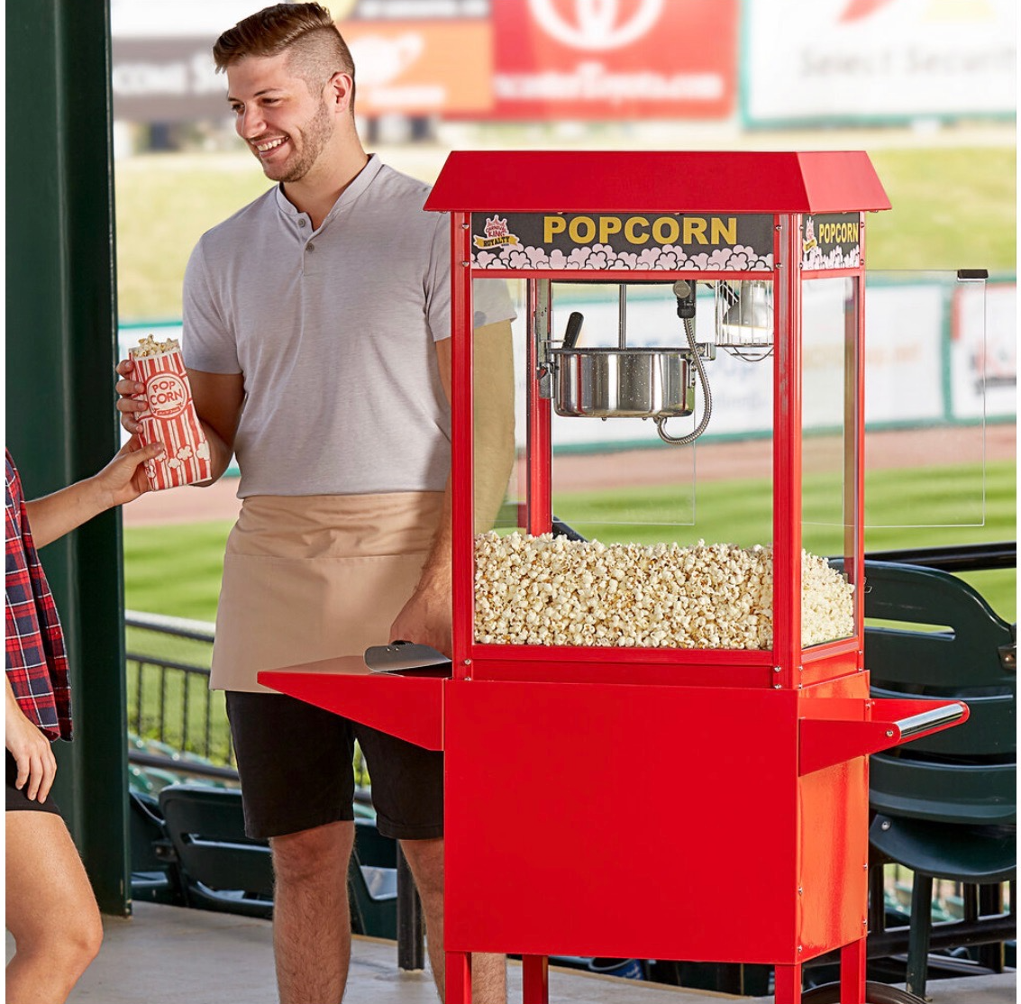 A man and woman standing next to a popcorn machine.