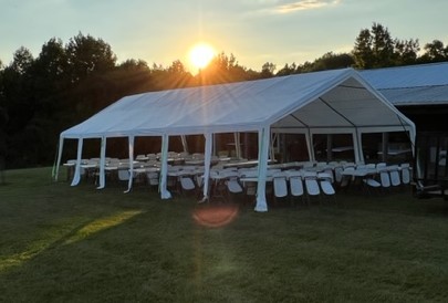 A large white tent with chairs in the grass.